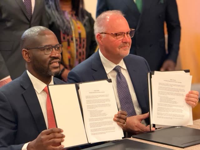 Two signatories presenting the signed agreement side by side